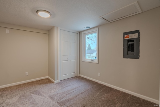 spare room featuring carpet, a textured ceiling, and electric panel