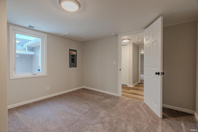 carpeted spare room with electric panel and a textured ceiling