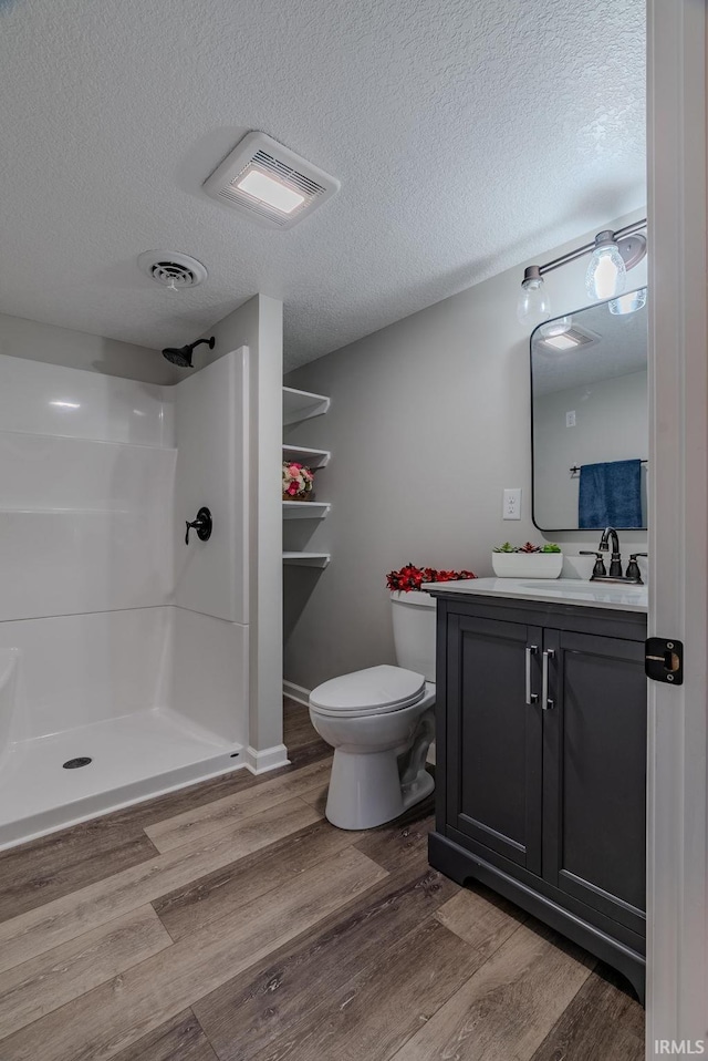 bathroom with vanity, a shower, wood-type flooring, and a textured ceiling