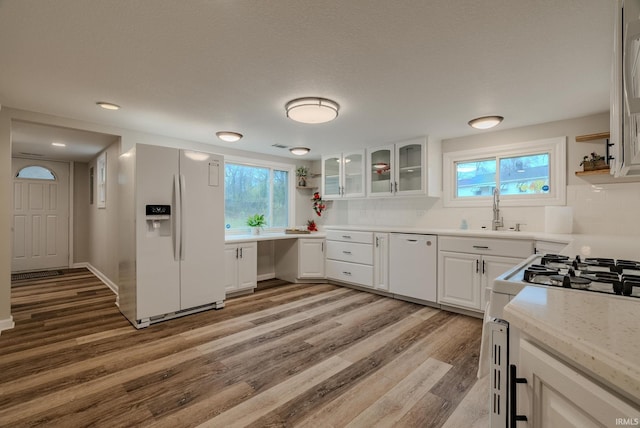 kitchen featuring light stone counters, white appliances, sink, white cabinets, and light hardwood / wood-style floors