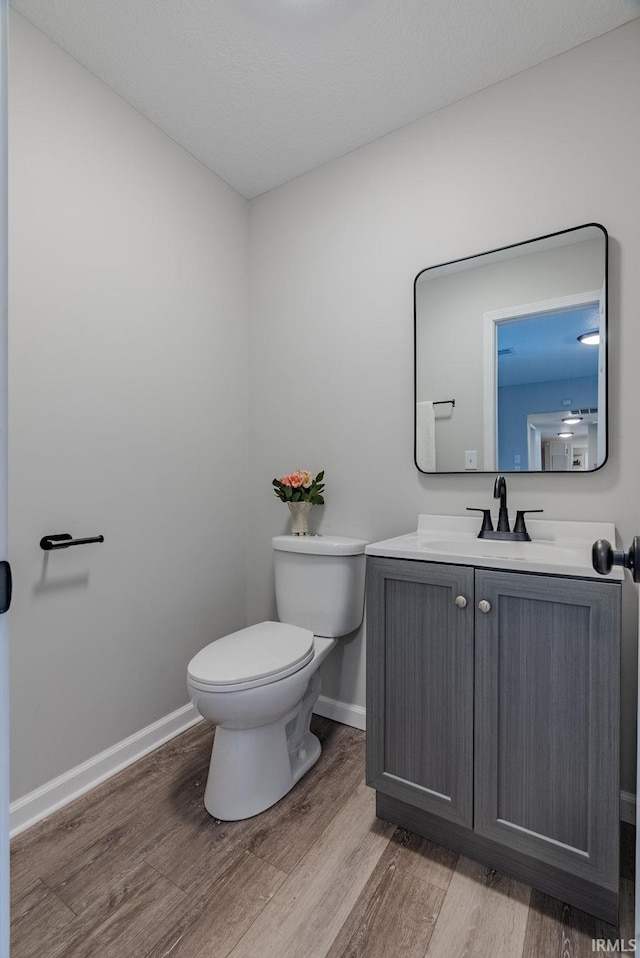 bathroom with hardwood / wood-style flooring, vanity, and toilet