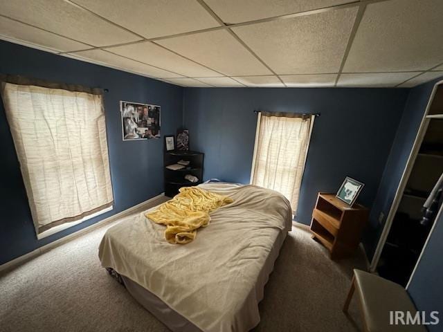 carpeted bedroom featuring a drop ceiling