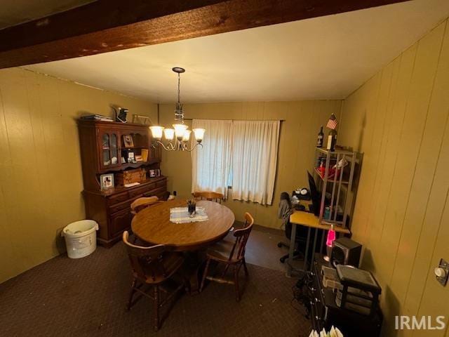 carpeted dining space with beam ceiling, wooden walls, and a notable chandelier