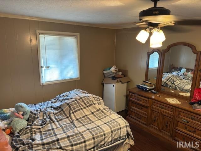 bedroom with a textured ceiling, ceiling fan, and dark hardwood / wood-style floors