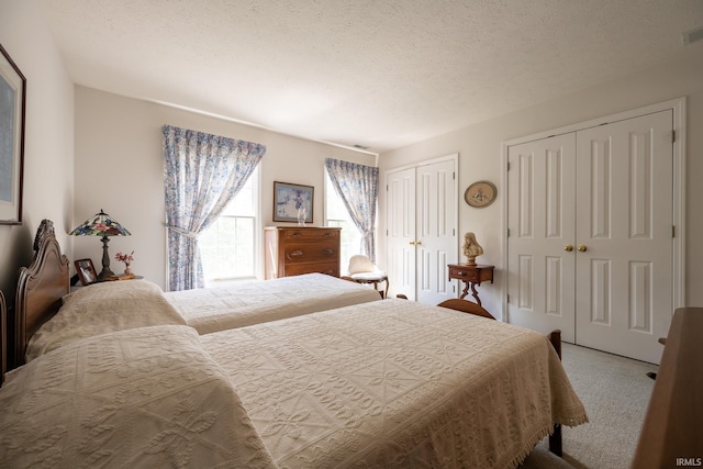 carpeted bedroom with a textured ceiling and multiple closets