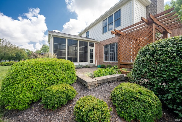 rear view of house featuring a sunroom and a pergola