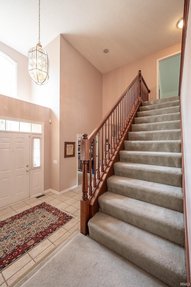 tiled entrance foyer with a towering ceiling and an inviting chandelier