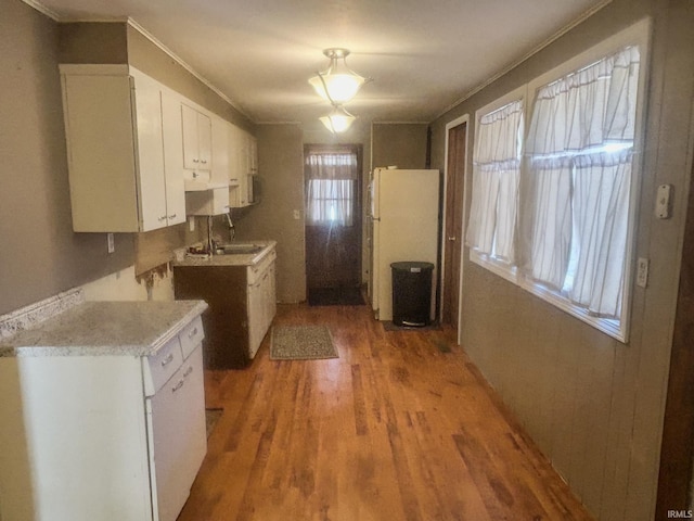 kitchen featuring hardwood / wood-style floors, white cabinets, white refrigerator, and sink