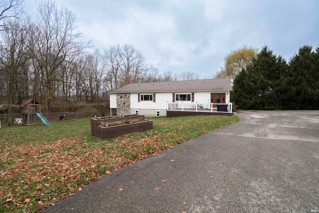 view of front of home featuring a playground, a deck, and a front lawn