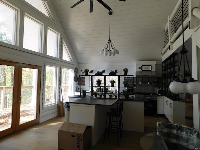 kitchen featuring kitchen peninsula, french doors, decorative light fixtures, light hardwood / wood-style flooring, and white cabinetry