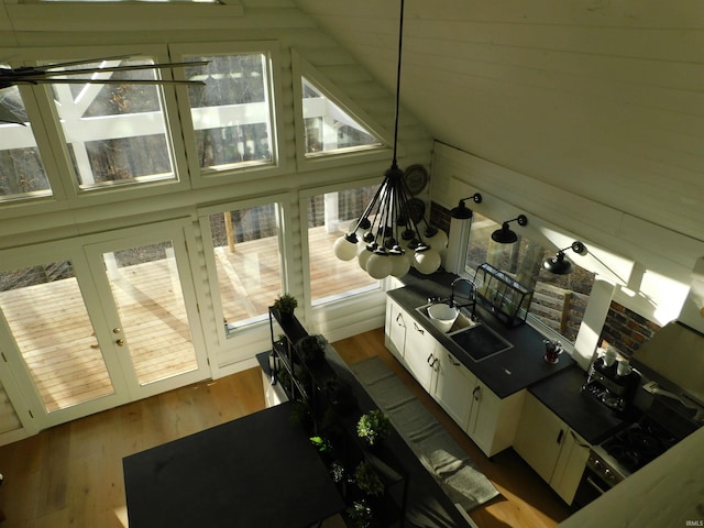 interior space featuring wood-type flooring, an inviting chandelier, white cabinetry, and lofted ceiling