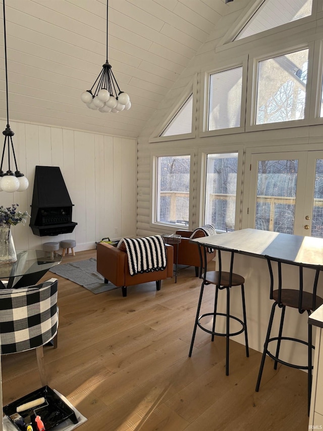 dining area featuring french doors, wood walls, light hardwood / wood-style flooring, and vaulted ceiling