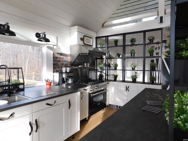 kitchen featuring white cabinetry, range hood, high end stove, light hardwood / wood-style floors, and lofted ceiling