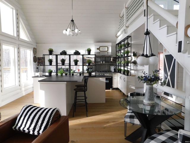 kitchen featuring a kitchen bar, gas range, white cabinetry, and hardwood / wood-style flooring