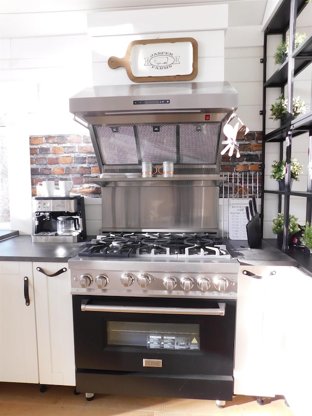 kitchen with white cabinets, high end stove, and extractor fan