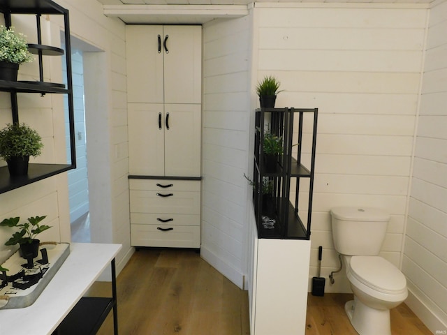 bathroom featuring hardwood / wood-style floors, toilet, and wooden walls