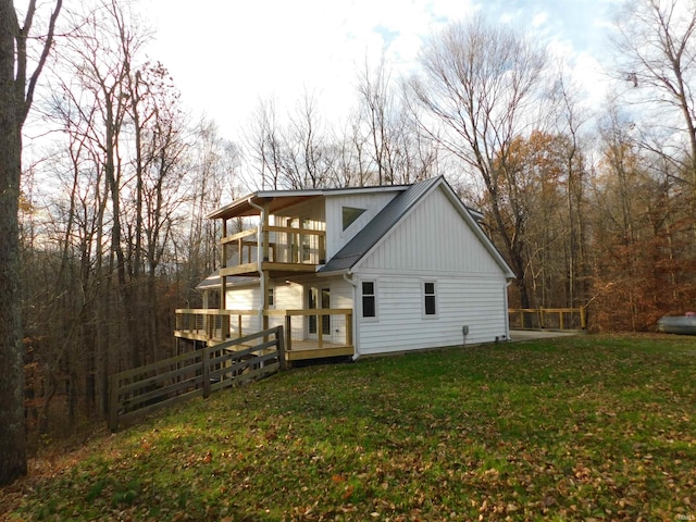 rear view of house featuring a balcony, a deck, and a lawn