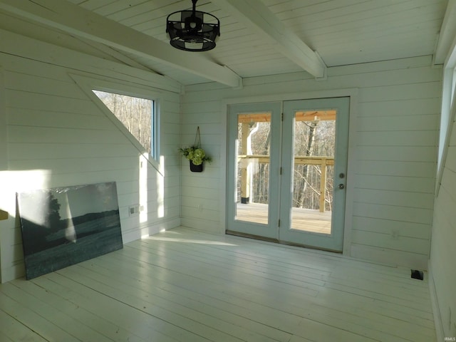 interior space featuring light wood-type flooring, lofted ceiling with beams, wooden ceiling, and wooden walls