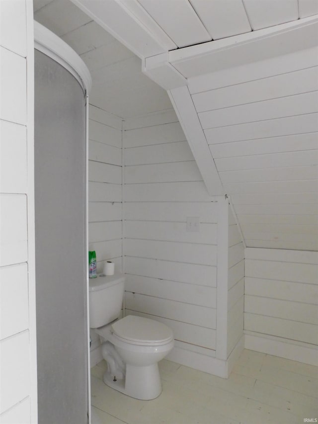 bathroom with tile patterned flooring, wood walls, and toilet