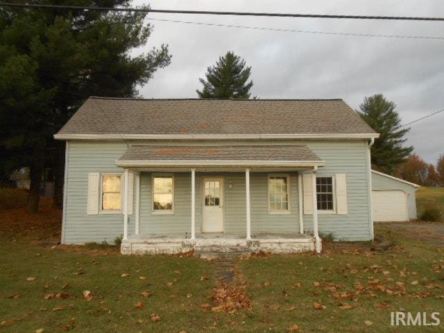 view of front of house with an outbuilding, covered porch, a front yard, and a garage