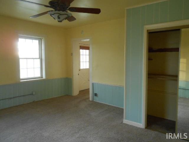 unfurnished bedroom featuring light carpet, a closet, multiple windows, and ceiling fan