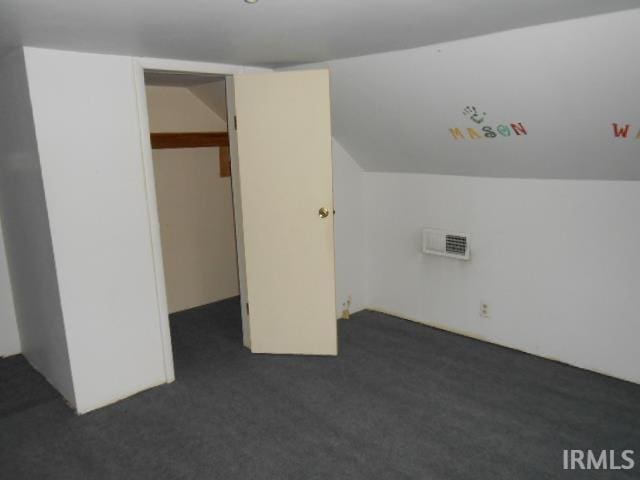 bonus room with dark colored carpet and vaulted ceiling