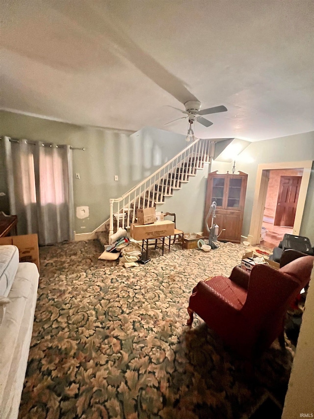 carpeted living room with ceiling fan and stairs