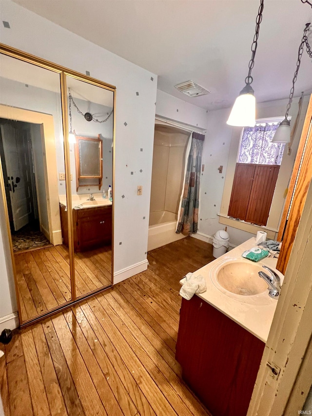 full bath featuring visible vents, shower / bathtub combination with curtain, hardwood / wood-style floors, vanity, and baseboards