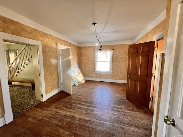 unfurnished dining area featuring stairs, dark wood-type flooring, baseboards, and wallpapered walls