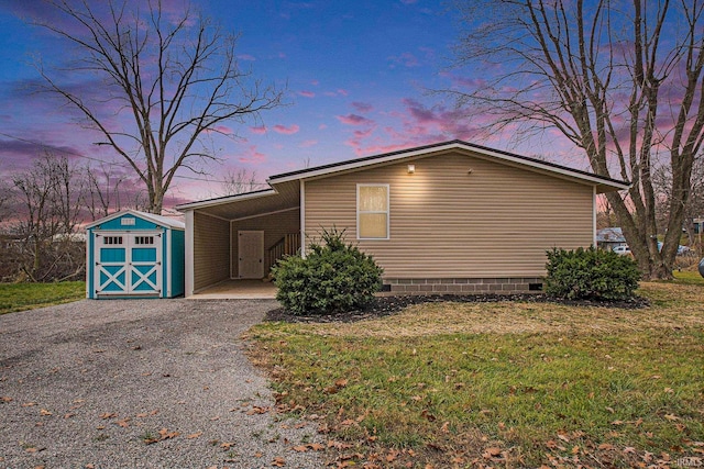 view of front of house with gravel driveway, a front lawn, a shed, a carport, and an outbuilding