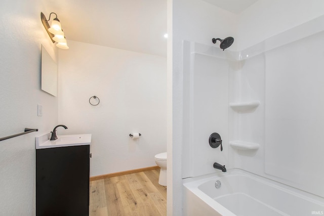 bathroom with baseboards, toilet, bathing tub / shower combination, wood finished floors, and vanity