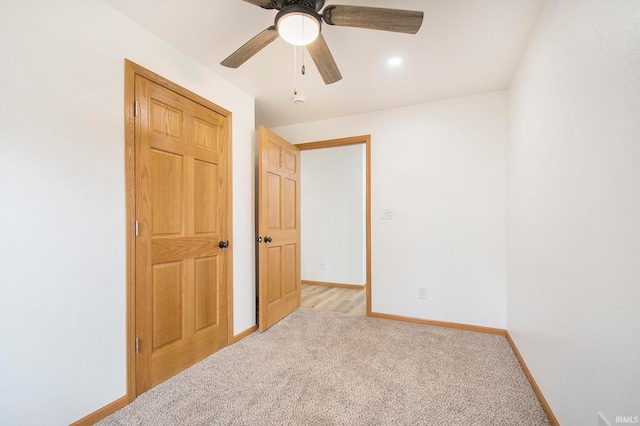 unfurnished bedroom with baseboards, light carpet, and a ceiling fan