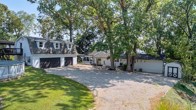 view of front of house featuring a pool side deck, a storage unit, a garage, and a front lawn