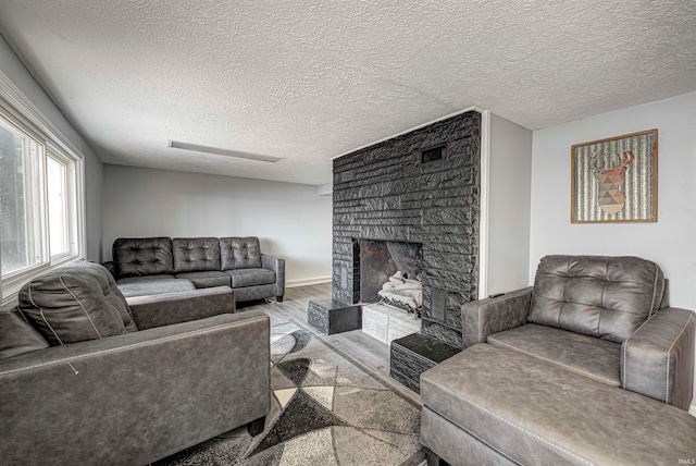 living room featuring a large fireplace, light hardwood / wood-style flooring, and a textured ceiling