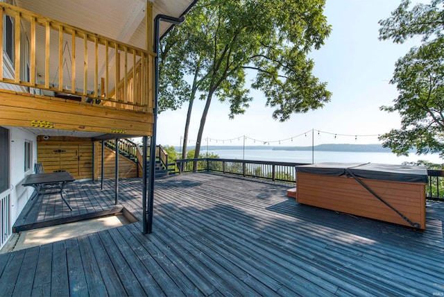 wooden terrace with a water view and a hot tub