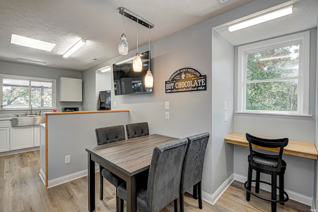 dining space featuring a textured ceiling, sink, plenty of natural light, and light wood-type flooring