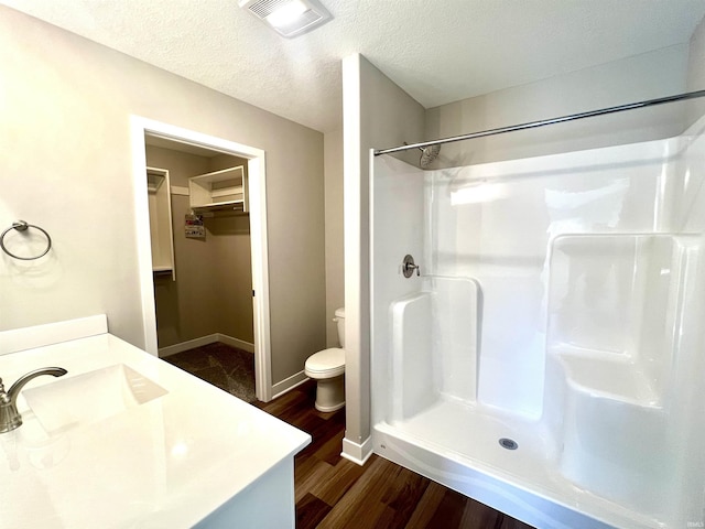 bathroom featuring hardwood / wood-style floors, a shower, vanity, toilet, and a textured ceiling