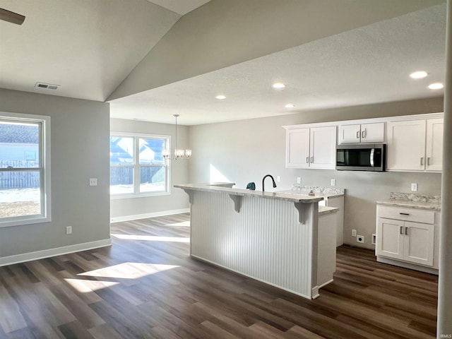 kitchen featuring white cabinetry, lofted ceiling, dark hardwood / wood-style flooring, and decorative light fixtures