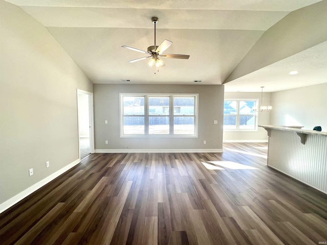 empty room featuring lofted ceiling, dark hardwood / wood-style floors, and ceiling fan with notable chandelier