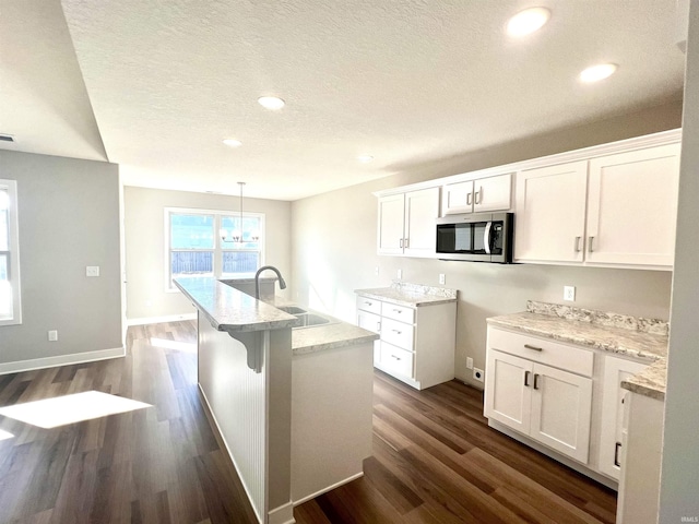 kitchen with white cabinetry, dark hardwood / wood-style floors, sink, and hanging light fixtures