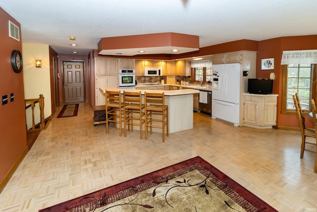 kitchen featuring a center island, white appliances, sink, a breakfast bar area, and light parquet flooring