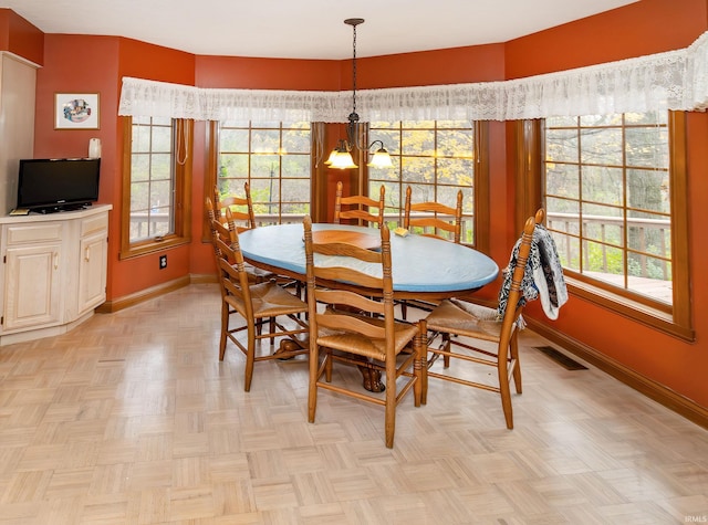 dining room with a chandelier, light parquet flooring, and a healthy amount of sunlight