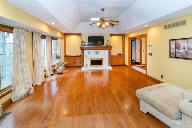 living room with lofted ceiling, light hardwood / wood-style floors, ceiling fan, and a healthy amount of sunlight