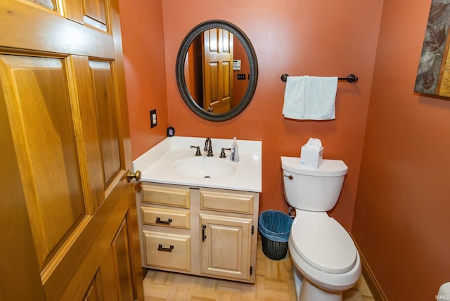 bathroom featuring vanity, toilet, and parquet floors