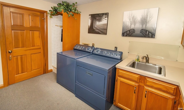 clothes washing area with cabinets, washer and clothes dryer, light colored carpet, and sink