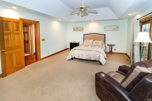 bedroom featuring a raised ceiling, ceiling fan, light carpet, and a textured ceiling