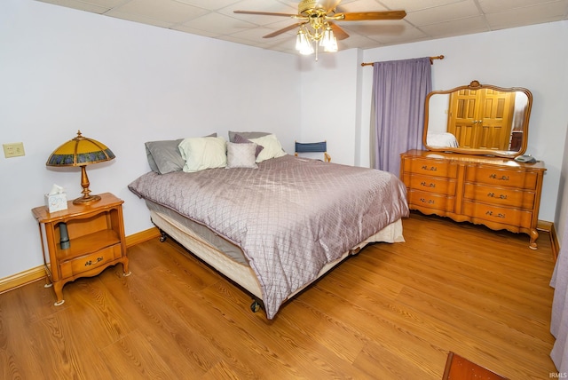 bedroom featuring hardwood / wood-style floors, a drop ceiling, and ceiling fan