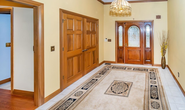 foyer entrance with crown molding and an inviting chandelier