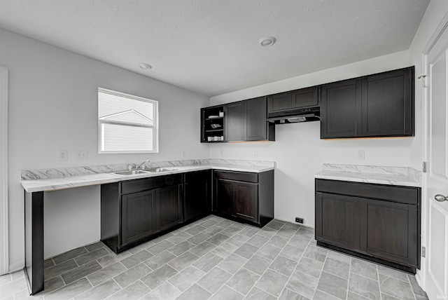 kitchen featuring light stone countertops, a textured ceiling, and sink