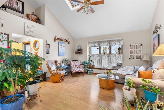 living room featuring ceiling fan, light wood-type flooring, high vaulted ceiling, and a skylight